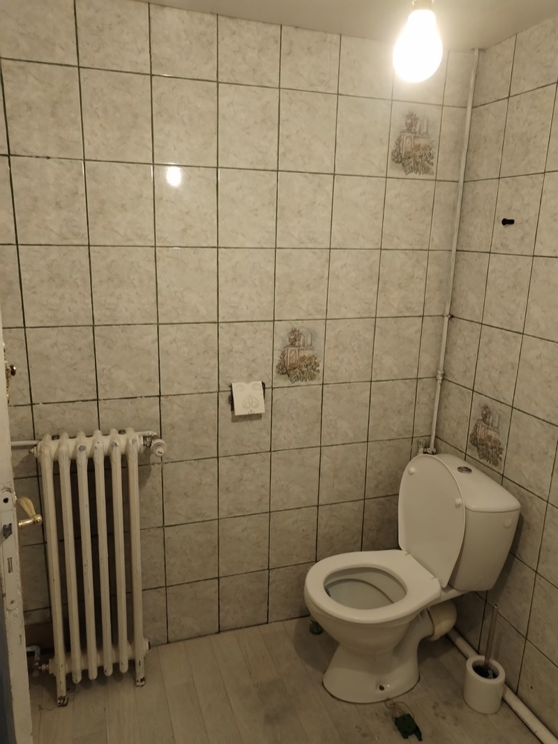 Avant : ancienne salle d'eau avec carrelage blanc fleuri et plomberie apparente
